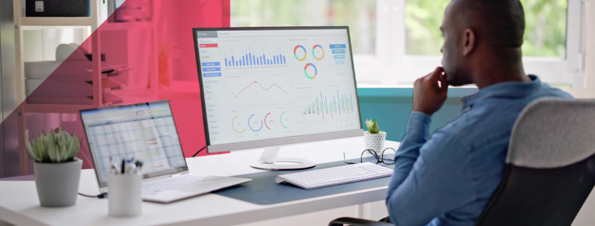 a man is sitting at a desk in front of a computer talking on a cell phone