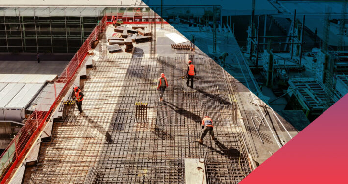 Aerial view of construction workers in safety vests and hard hats installing a dense steel rebar grid