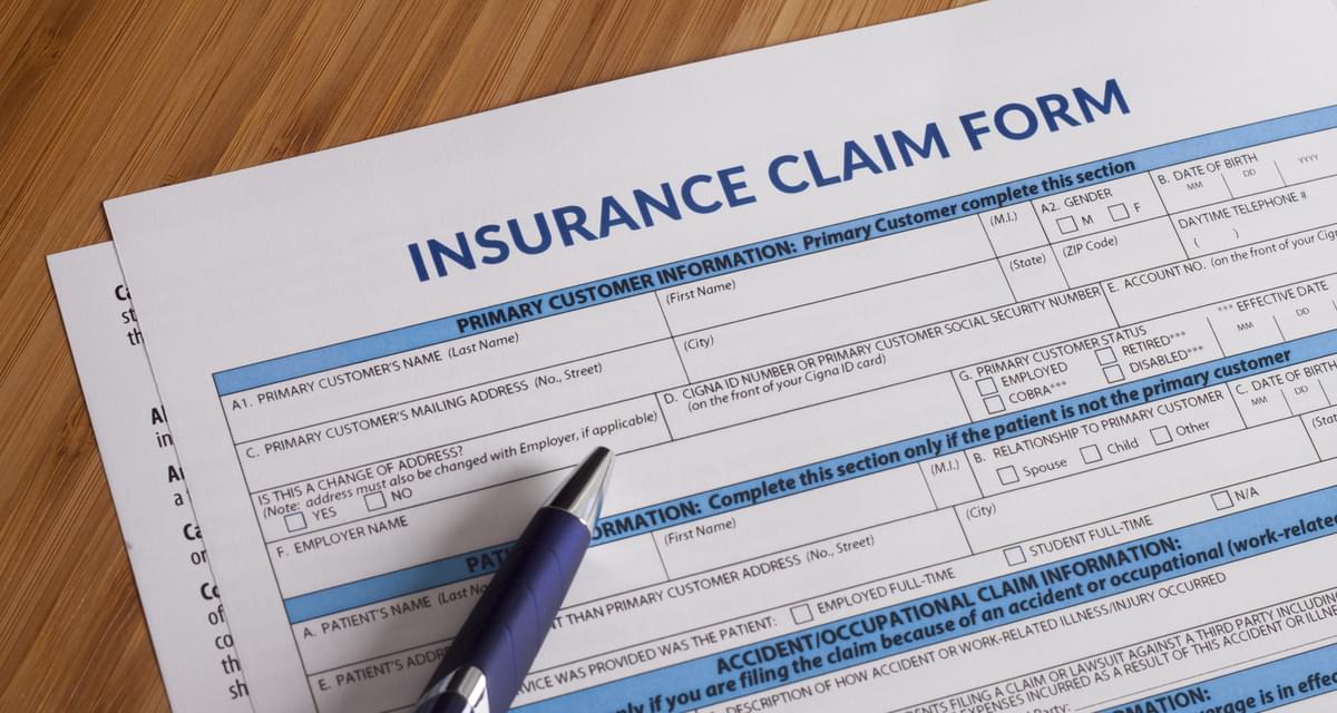 a blue pen sits on top of an insurance claim form